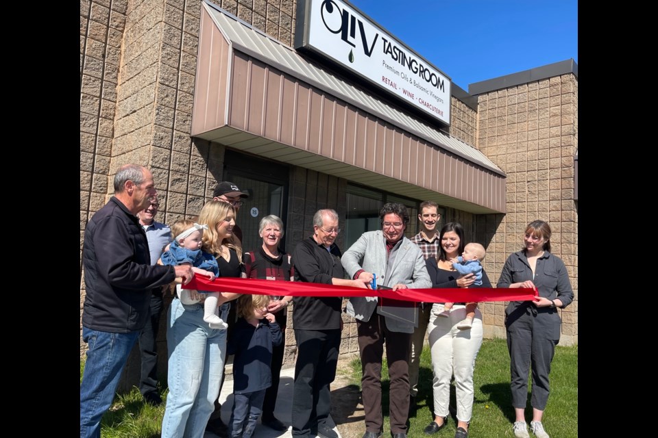 Cutting the ribbon outside the new  OLiV location are Rod Jorgenson, All Huiberts (rear) Bianca Silvestri and her little one, Matt Smith (hidden), Colleen Cone, Rick Jorgensen, Lord Mayor Gary Burroughs, Taylor Whitty, Olivia Carovillano and their son Nicco, and Becca Jorgensen.