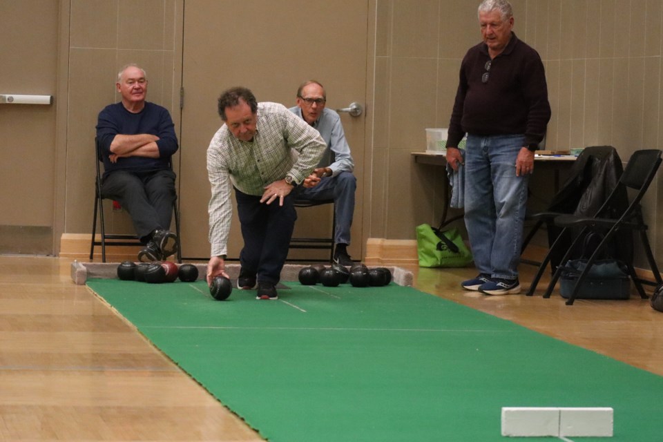 First-time bowler Jim Brown, attending the first session at the community centre this season, tries his hand with some pointers from some more experienced short mat bowlers.
