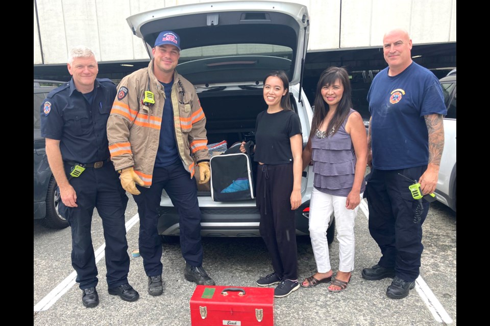 West Vancouver Fire & Rescue members pose with the grateful family of the cat they'd just rescued (stowed safely in the crate), July 6, 2022.