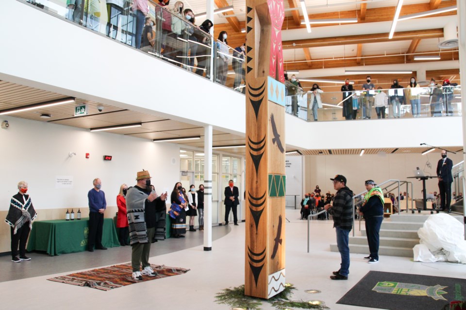 Sxwíxwtn (Wilson Williams, striped shirt), one of the witnesses to the ceremony, speaks to Sinàmkin, Jody Broomfield, Coast Salish artist and the audience.