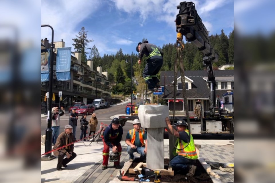 Local artist Greg Kawczynski (left) looks on as workers reinstall his sculptures outside the Deep Cove Cultural Centre.