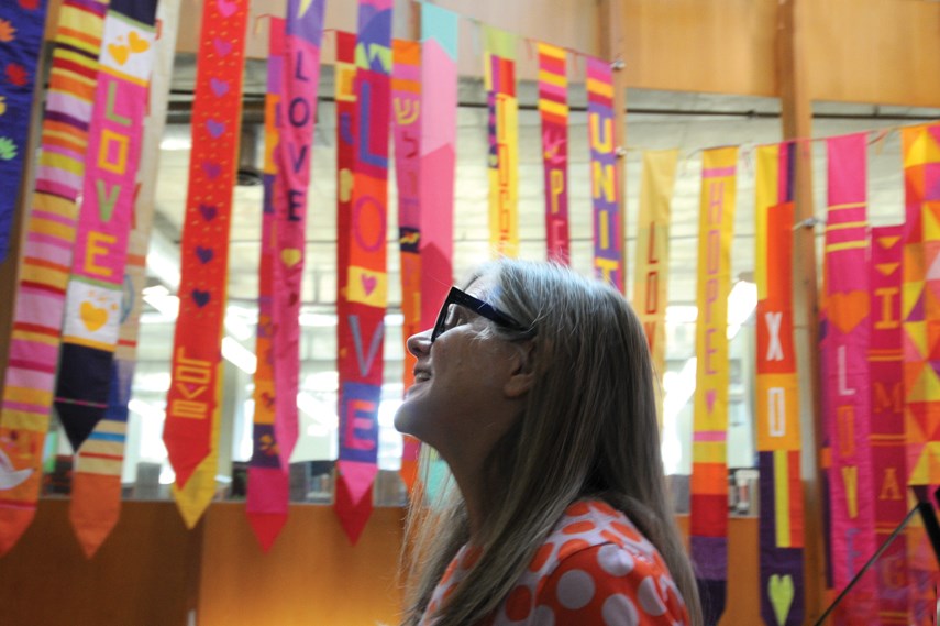 Artist and organizer Berene Campbell stands under a banner of quilts in the stairwell at Lynn Valley library after they were installed on July 19, 2021. The massive community project has been underway for months, following the tragic stabbing event of March 27, 2021. 