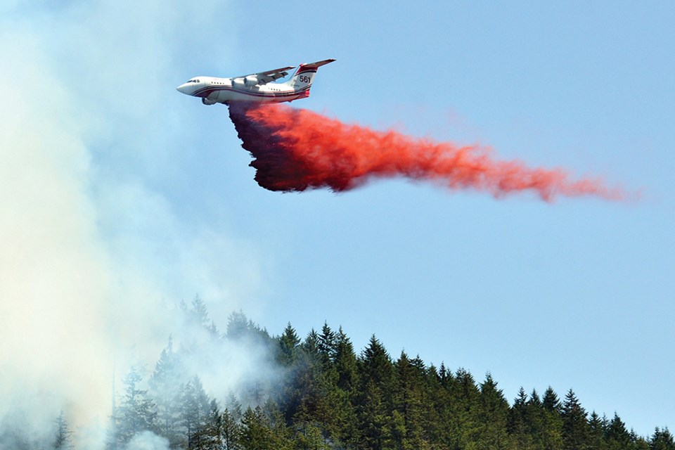 An aircraft drops fire retardant on a fast-moving fire near Horseshoe Bay in West Vancouver on June 26, 2023.
