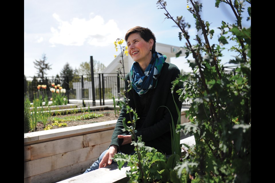 Mackenzie Stonehocker tends plants in the Driftwood Village co-housing complex's rooftop garden.