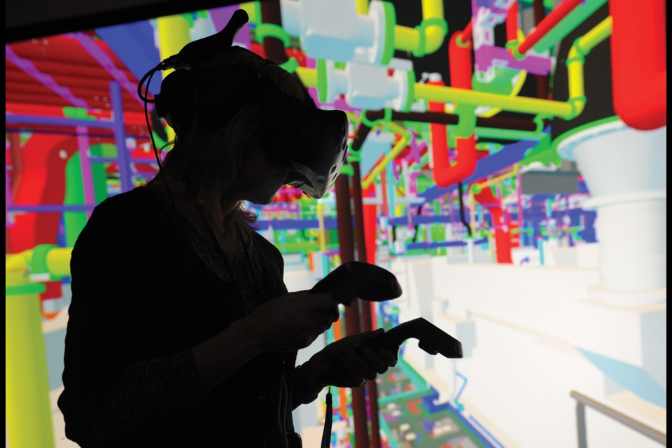 An individual wearing a VR headset "walks through" the oceanographic vessel's engine room in Seaspan's immersive HoloShip VR program.