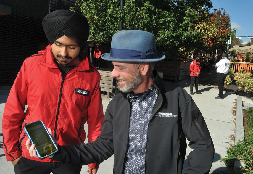 Lower Lonsdale Business Improvement Area executive director Greg Holmes checks out his vaccine status with Rajan Singh of Goldilox Security outside the restaurant strip by the Shipyards, Sept. 13.