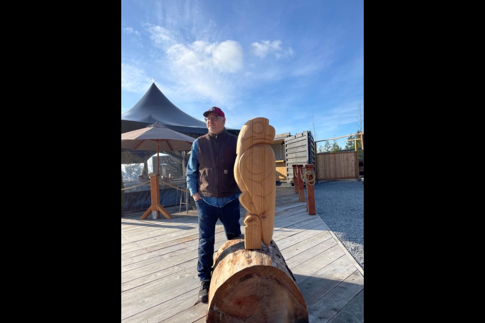 Sḵwx̱wú7mesh (Squamish) carver Tawx'sin Yexwulla (Aaron Nelson-Moody) stands next to his “Cypress Eagle" which now sits at the entrance to Cypress Pop-Up Village.