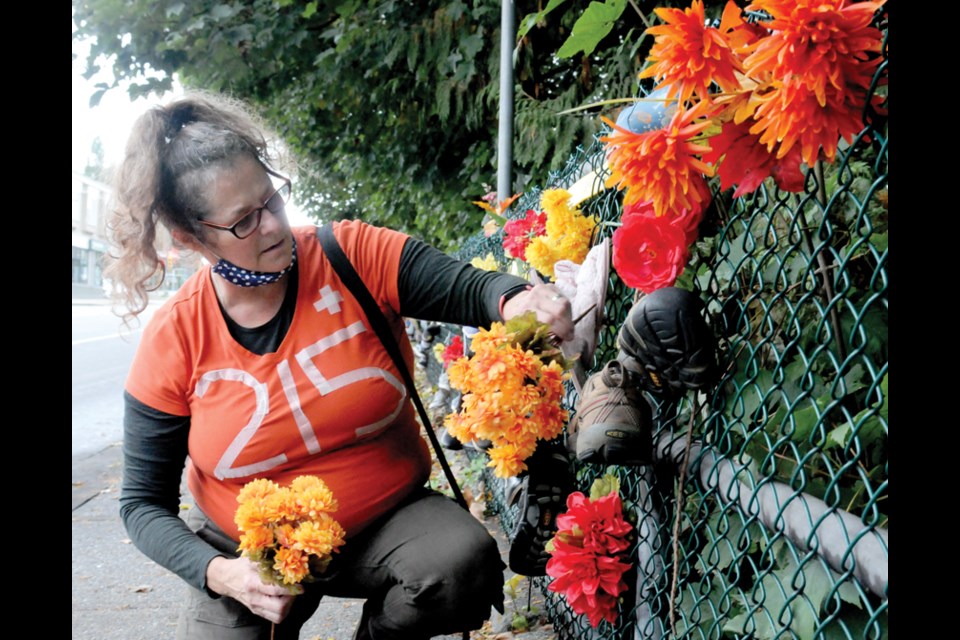 Gwyneth Sobejko adds to the 'Memorial 215 + Lest We forget' she started on Canada Day 2021 on Lynn Valley Road just east of Mountain Highway.