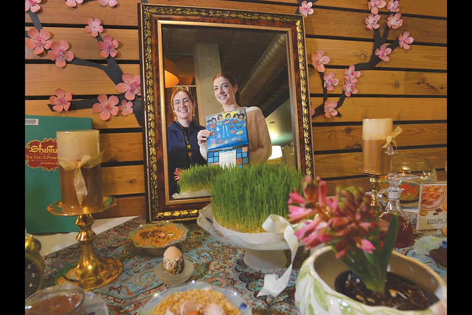 Assistant librarians Ashley Watson and Cassandra Casley of the Lynn Valley branch of the North Vancouver District Public Library reflect on the Nowruz table created by fellow library staff member Parvin Golbargi. | Paul McGrath / North Shore News