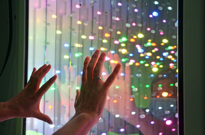 A user tests out a mirrored panel, full of bright LEDs that appear as if they're stretching out into infinity, part of North Shore Disability Resource Centre's new mobile Snoezelen room. 