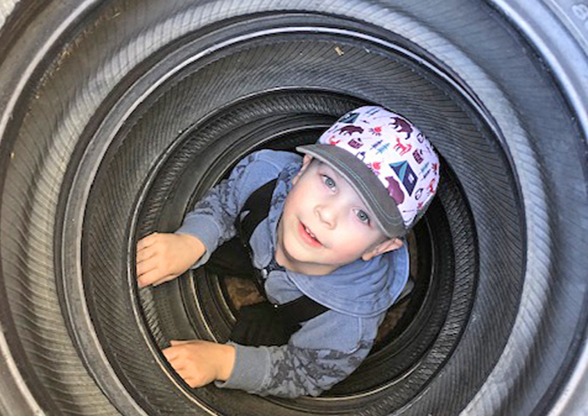 Sam explores the inner workings of a set of tires during outdoor play at Mount Seymour Preschool earlier this year. After 50 years, the North Vancouver preschool is closing this month. 