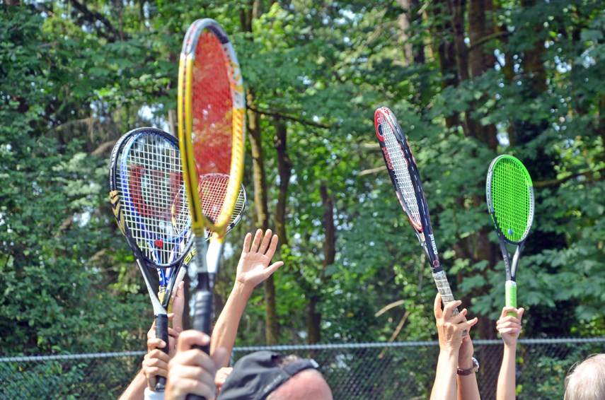 Tennis players hoist their rackets during a planned sit-in at the tennis courts at North Vancouver's Little Cates Park on July 2, 2021.