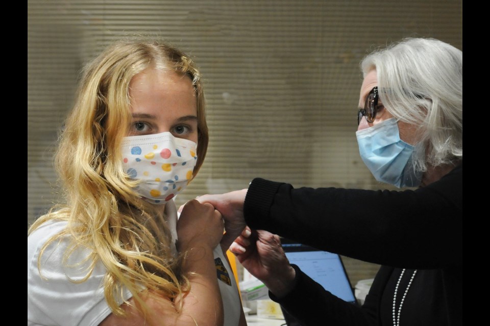 Madeleine Hatswell, 11, receives a COVID vaccine at the North Vancouver clinic Dec. 6 from retired nurse Mary Radmanovic