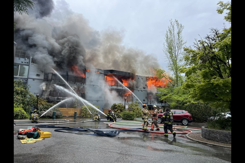 Flames pour out from Silverlynn Apartments in Lynn Valley on Saturday morning. Firefighters work to knock down the blaze. | Pat Bell