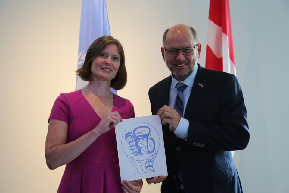 Jaime Webbe, president and CEO of the UN Canada, presents Gordie Dick's artwork to the Swedish Ambassador to Canada, Urban Ahlin. 