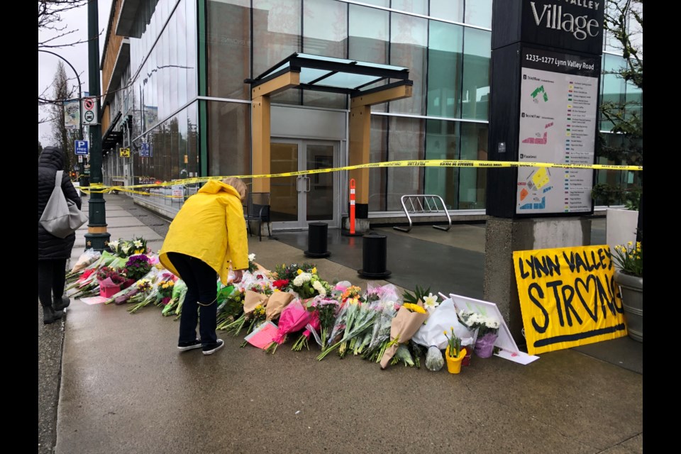 A resident lays flowers at a memorial to a victim of a stabbing in Lynn Valley in March 2021.