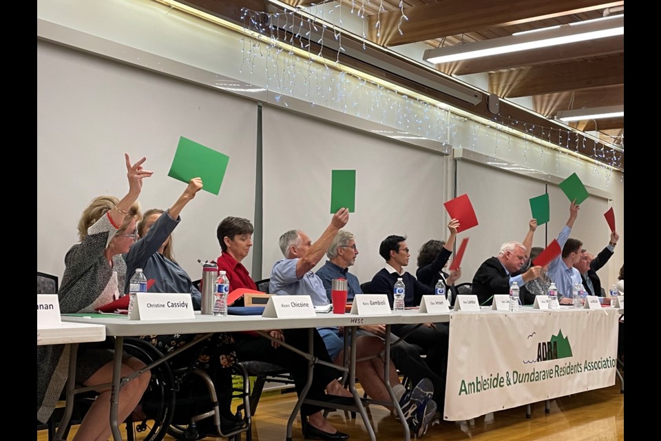 Candidates hold up red and green squares indicating "yes" or "no" answers to questions at a West Van all-candidates forum.