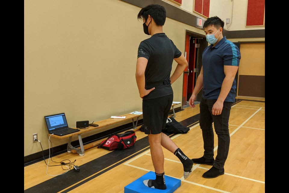 Alex You from the North Shore Basketball Academy completes a balance assessment with kinesiologist Mathieu Gagnon from the Surrey Neuroplasticity Clinic. 
