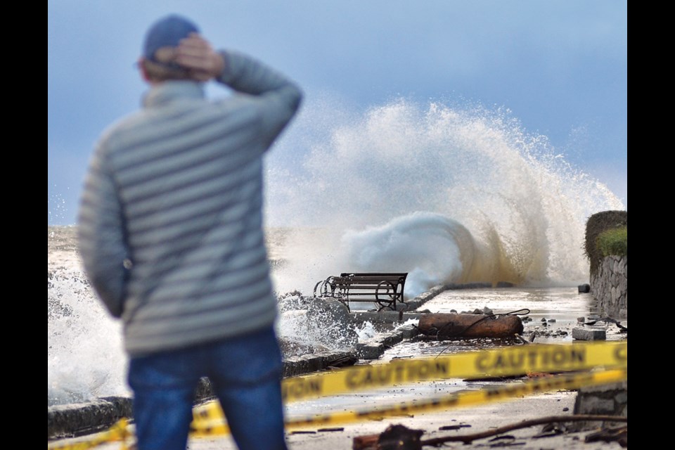A West Vancouver residents gets a peek at waves crashing on Centennial Seawalk. The District of West Vancouver closed the path Monday, Nov. 15 due to the storm.