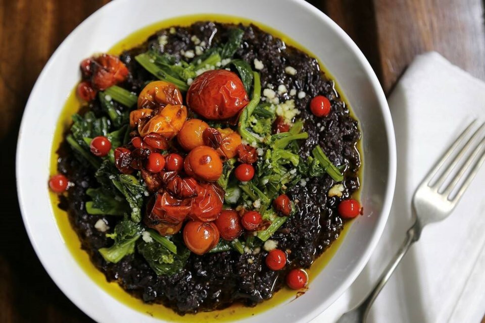 Charred currant, red, pink, gold, yellow and white cherry tomatoes on black rice risotto. | Laura Marie Neubert 