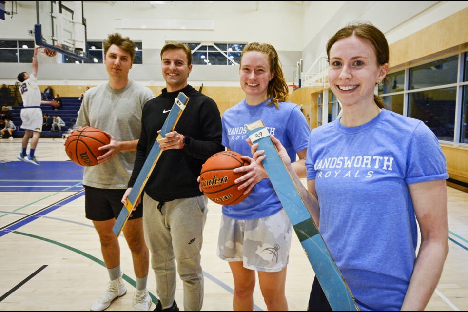 Handsworth basketball alumni Conor Power, Luka Petkovic, Lianna Rushworth and Diana Lee show floorboards from the old school's gym, which are being auctioned off to buy new equipment. | Nick Laba / North Shore News 