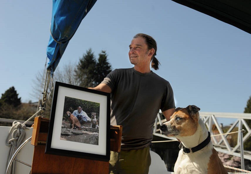 Matthew Witt and Rio on their family sailboat in April 2021. Matthew holds a photo of his son Sebastian who died in 2015 of a fentanyl overdose. | Mike Wakefield / North Shore News 