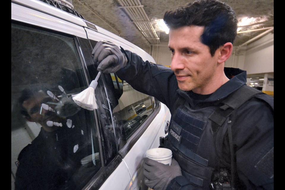 North Vancouver RCMP Cpl. Robert Otto demonstrates fingerprint dusting techniques on a vehicle window. | Paul McGrath / North Shore News 