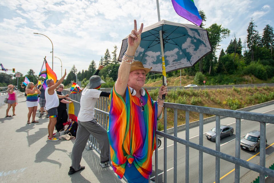 Stalwart activist Chris Bolton, known for his drag persona Conni Smudge, throws up a peace sign on the Mountain Highway overpass in North Vancouver on July 20. | Nick Laba / North Shore News 