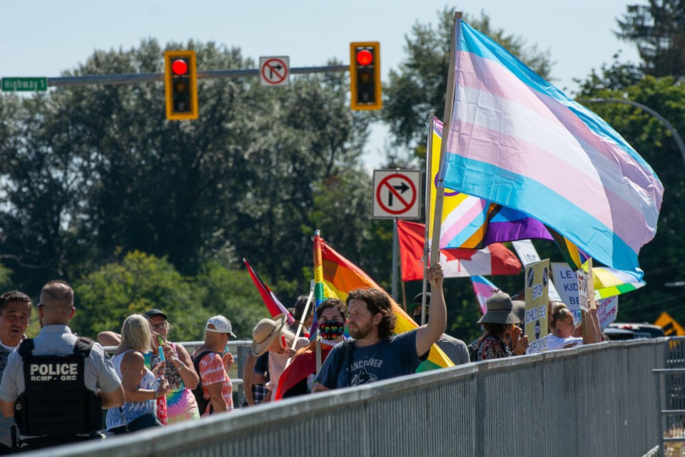 RCMP officers watch on as usual demonstrators and pro-2SLGBTQIA+ counter-protestors wave flags and display signs on the Mountain Highway overpass in North Vancouver. Nick Laba / North Shore News 