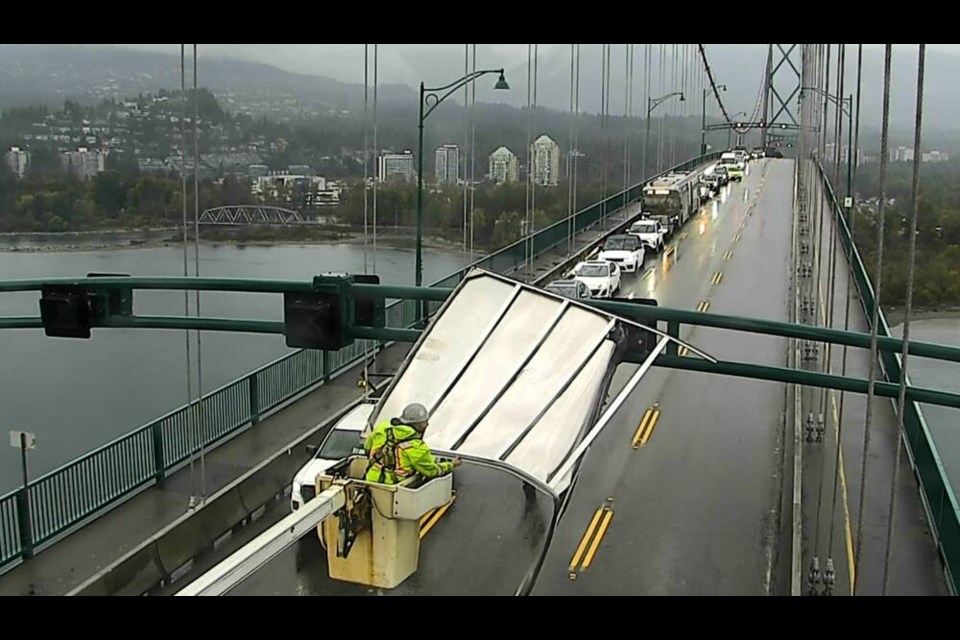 Crews work to dislodge a large metal object that got wrapped around an overhead section of the Lions Gate Bridge. | DriveBC 
