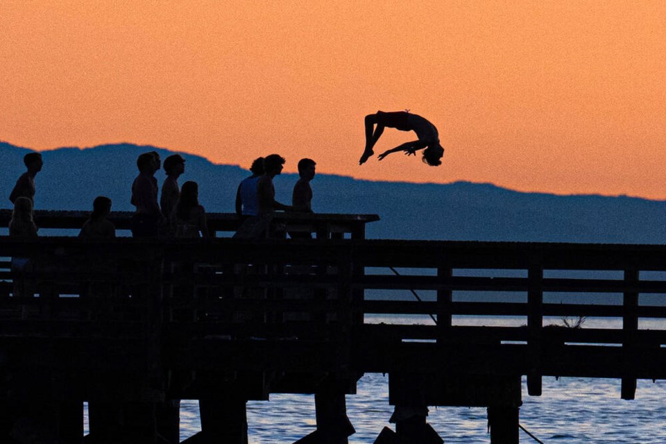 A young man does a back flip from West Vancouver’s Ambleside Pier. | Mark Teasdale 