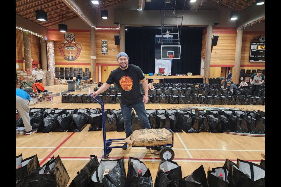 Jacob Lewis lends a hand as 900 bags are packed by Squamish Nation staff and volunteers for delivery to families in time for Christmas. | Tannis Louie