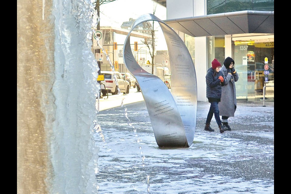 Bundled up passerbys walk past a frozen fountain at City of North Vancouver Civic Plaza on Jan. 12 when temperatures dipped to a record-breaking –12.8 on the North Shore. | Paul McGrath / North Shore News 