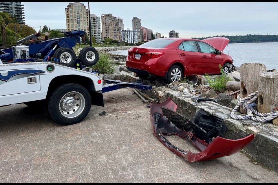 A car is removed after a driver smashed through cement boulders and came to a halt on the rocky shoreline Friday on the West Vancouver waterfront. | Penny Ihaksi 