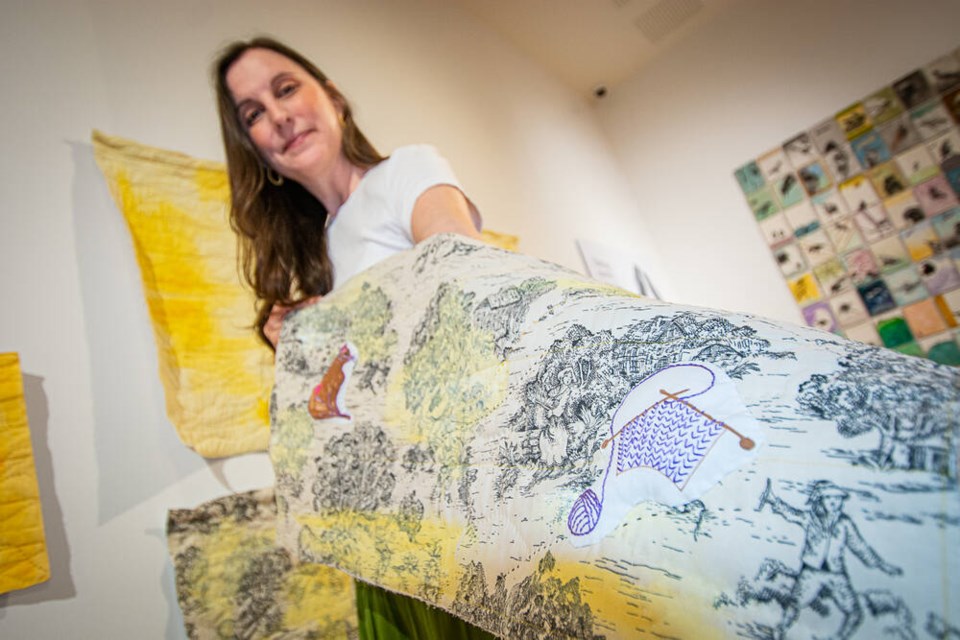 Mixed media quilter Jennie Johnston holds a panel from ‘A Light in the Window: Symbols of Memory,’ an evolving artwork on display in MONOVA’s feature gallery. | Nick Laba / North Shore News 