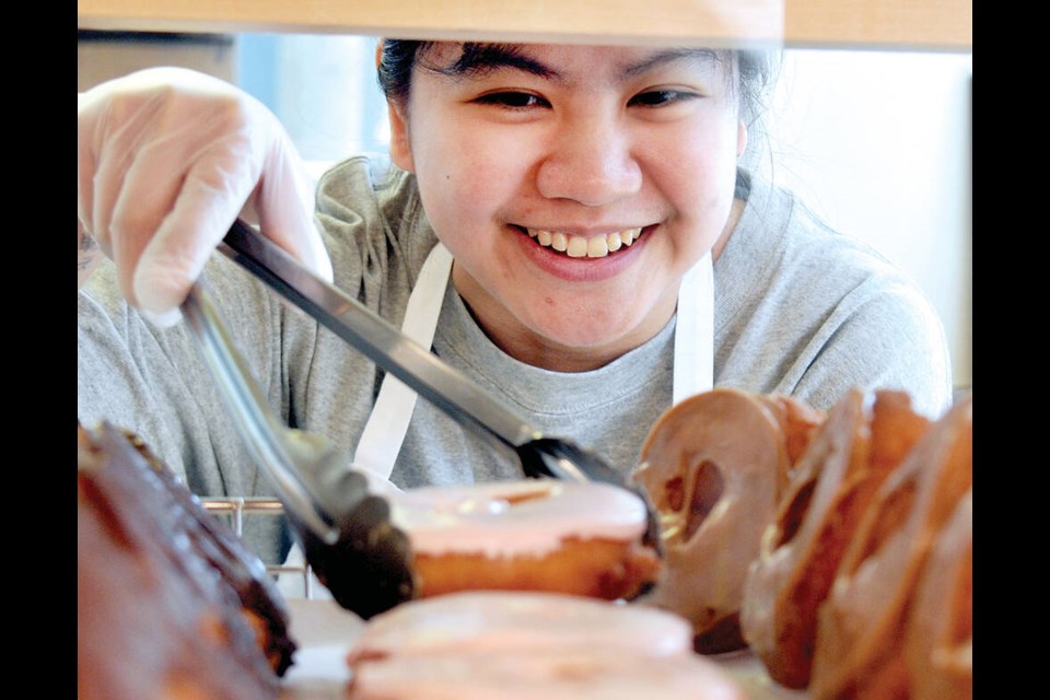 Lee’s Donuts supervisor Ana Pedro picks a fresh doughnut at the company’s new location in Lower Lonsdale. | Paul McGrath / North Shore News 