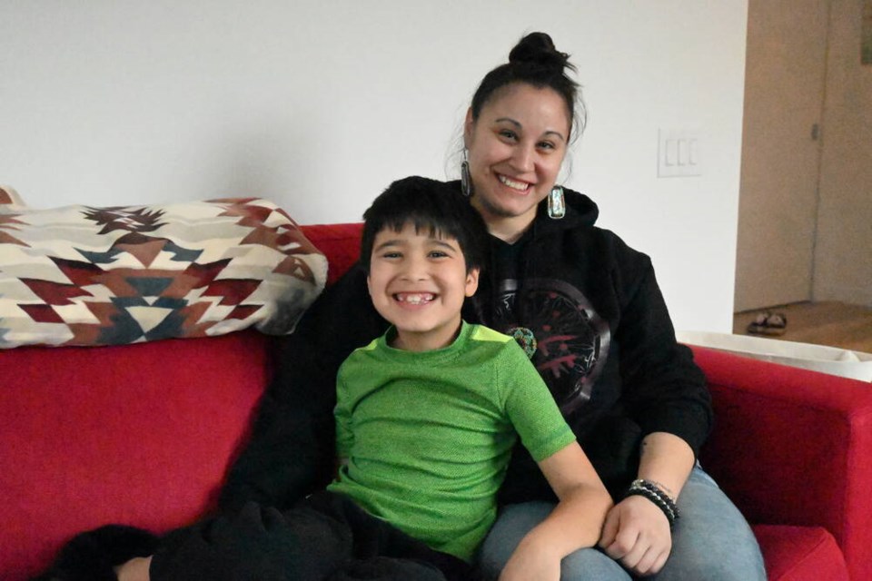 Anneliese Vonkanel and her eight-year-old son sit on their couch in their two-bedroom apartment in the Chenkw Em̓út building. | Abby Luciano / North Shore News 