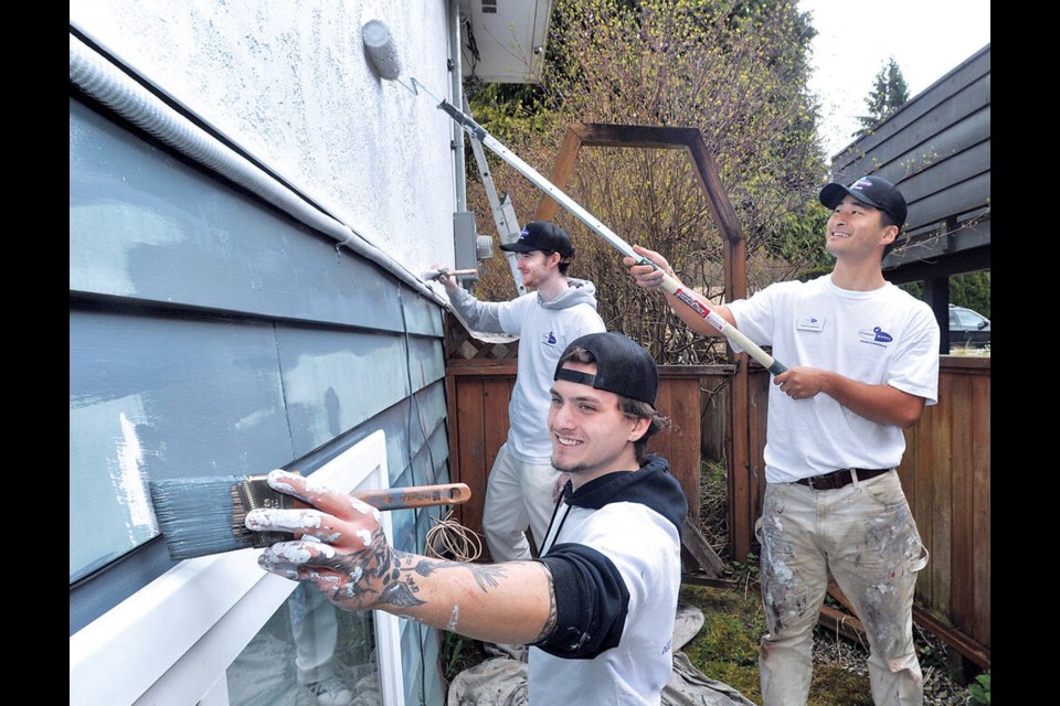 Student Works Painting workers Jesse Bishop (left), Tomoki Okamura and Jack Ross (rear) apply paint to a North Vancouver bungalow style home for a woman who has Stage 4 cancer. The free paint job is part of the company's charity work. | Paul McGrath / North Shore News 