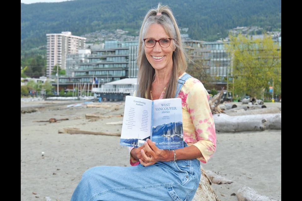 North Shore author Lindy Pfeil sits on a log in Ambleside Park with her latest compilation of West Vancouver Stories, with this edition focusing on wellness. | Paul McGrath / North Shore News 