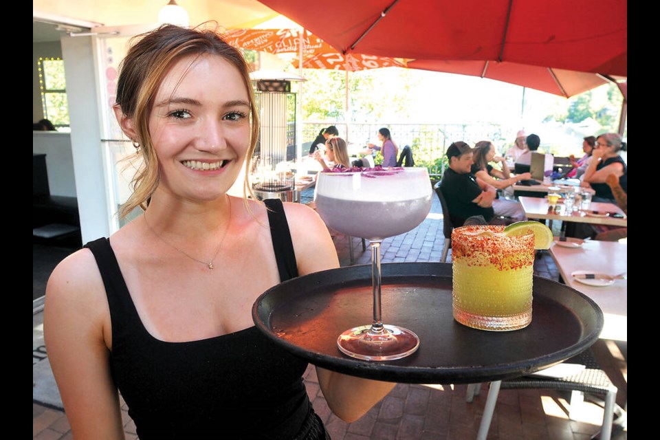 Arms Reach Bistro server Kiera serves some summer cocktails on the patio in Deep Cove. | Paul McGrath / North Shore News 