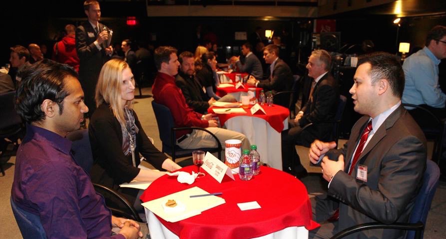 Younger adults talking to Business People around a table | Oakville United Way