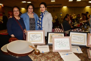 Three ladies standing behind a table | Maryam Rostami. Sabrina Armahi & Parisa, Director of the Nowruz Celebration; Photo Credit: Janet Bedford | Janet Bedford