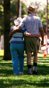 Elderly couple with there arms around each other walking in a park