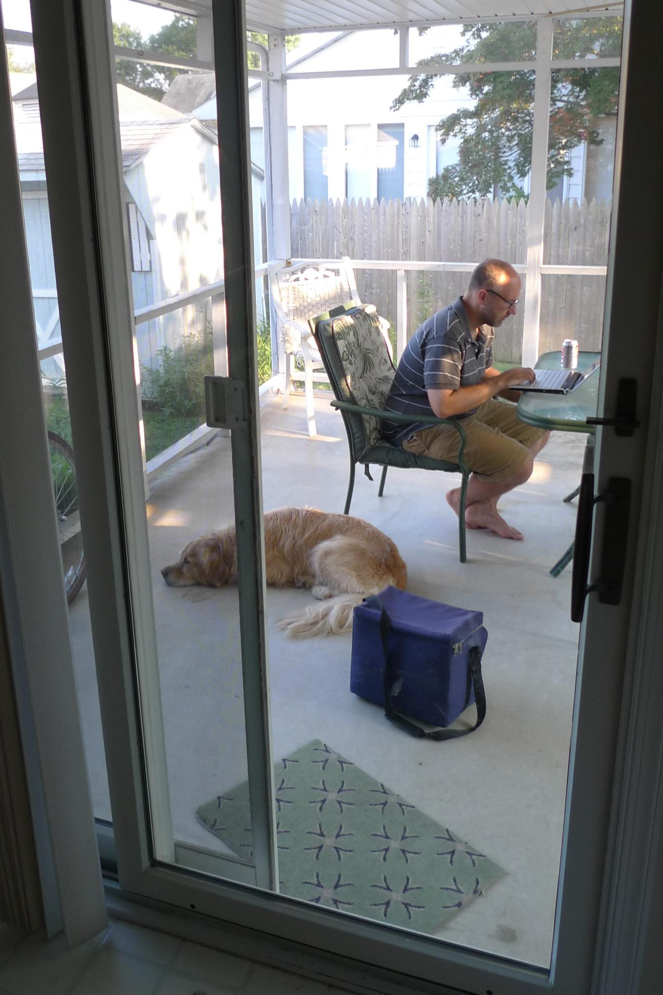 Man working on a computer on the porch with dog at his feet | Photo credit: jsmjr  -  Foter  -  CC BY-SA
