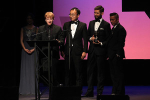 two white man and two black men at podium in tuxedos | Alexander Poei (far right) on stage with his team that received the Annie Award for Outstanding Achievement, Character Animation in a Live Action Production for The Revenant - The Bear; Photo Credit: David Yeh, courtesy of the Annie Awards | David Yeh, courtesy of the Annie Awards