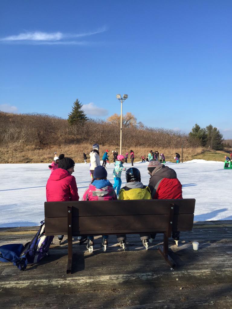 four people on a bench overlooking the ice rink preparing to skate | Bronte Creek Provincial Park
