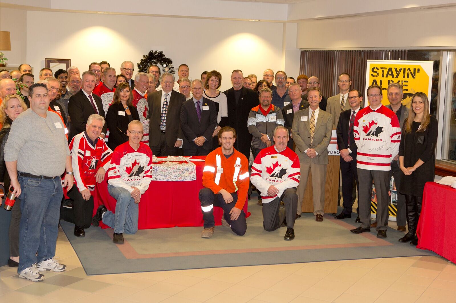 formal photo of 50 people around a signed jersey | Oakville Hyrdo