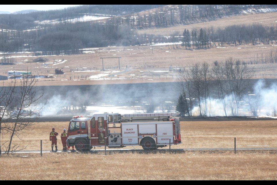 Firefighters tackle hotspots following a grass fire near Turner Valley on Feb. 12.