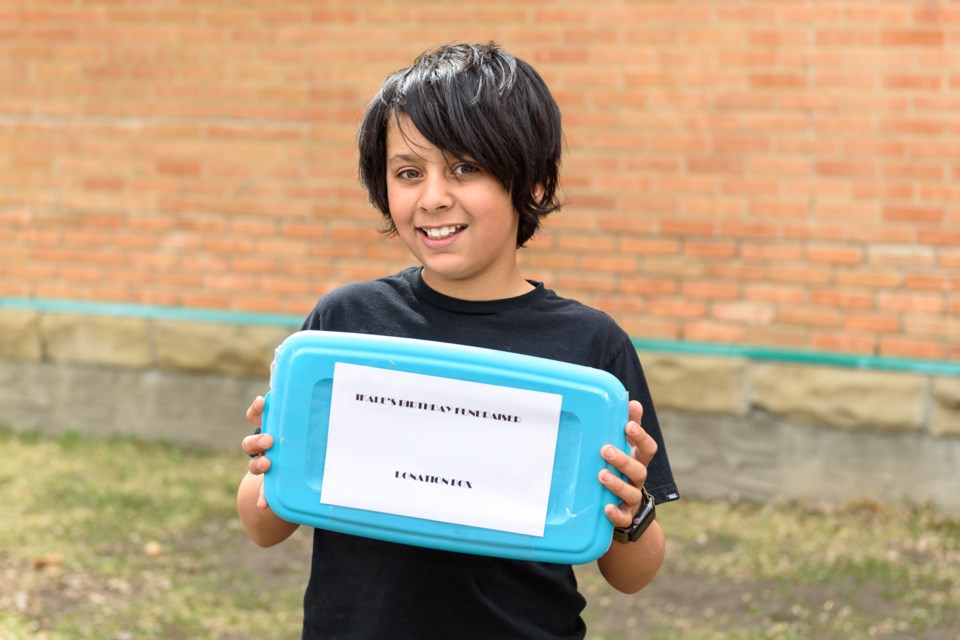 Ikale Lowe raised $640 for Pound Rescue for his birthday, and displays a container holding the money in Okotoks on May 5. 