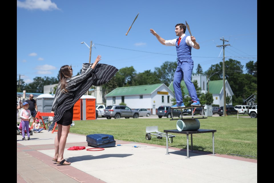 Circus artist Jason Melnychuk has a spectator pass him knives to juggle as he performs a balancing act during Okotoks BuskersFest in 2022.  This year’s event takes place June 24 in downtown Okotoks.